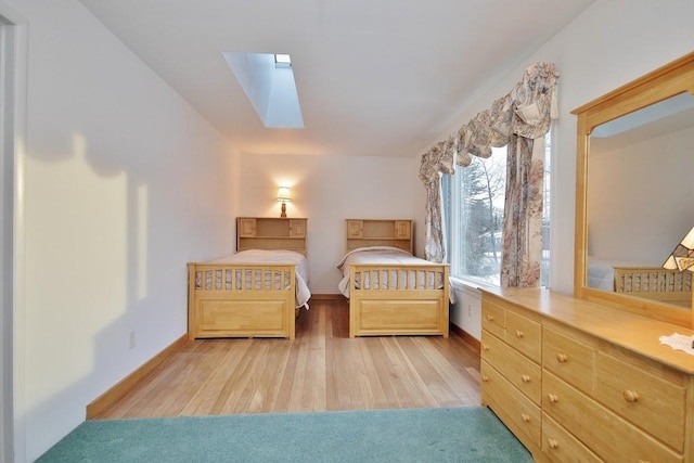 unfurnished bedroom with baseboards, wood finished floors, and a skylight