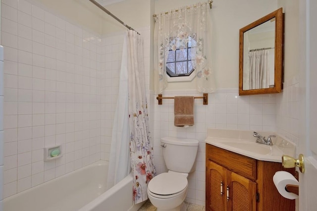 bathroom with vanity, a wainscoted wall, shower / bath combination with curtain, tile walls, and toilet