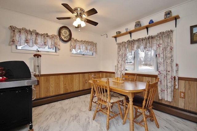 dining area with a wainscoted wall, baseboard heating, marble finish floor, and ornamental molding