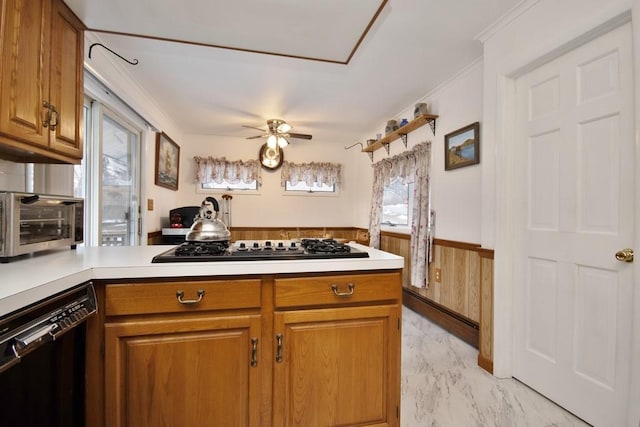 kitchen featuring a wainscoted wall, a peninsula, gas stovetop, light countertops, and dishwasher