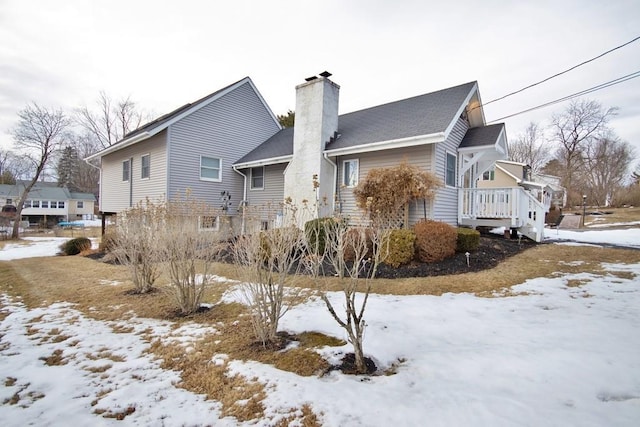 snow covered property with a chimney