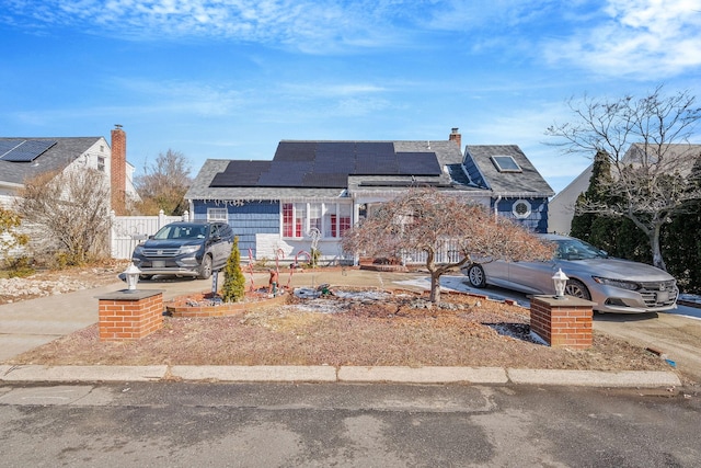 view of front of house with roof mounted solar panels and a chimney