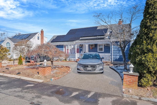 view of front of home with solar panels, aphalt driveway, and a chimney