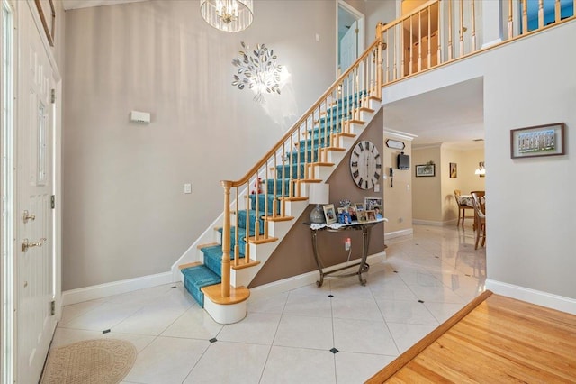 staircase with a high ceiling, baseboards, ornamental molding, and tile patterned floors