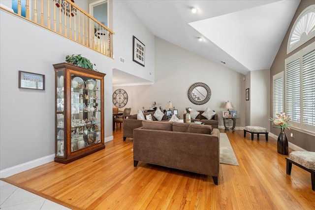 living room featuring light wood-type flooring, visible vents, high vaulted ceiling, and baseboards