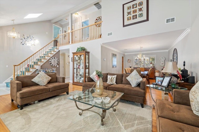 living area featuring an inviting chandelier, stairway, visible vents, and wood finished floors