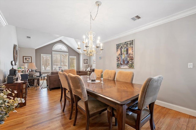 dining area featuring light wood finished floors, baseboards, visible vents, lofted ceiling, and crown molding