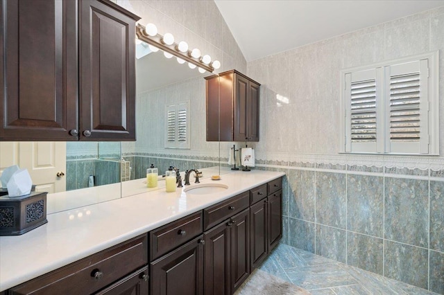 full bath with lofted ceiling, tile walls, and vanity