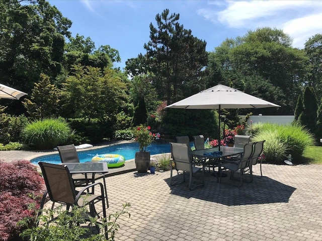 view of patio featuring outdoor dining space, fence, and an outdoor pool