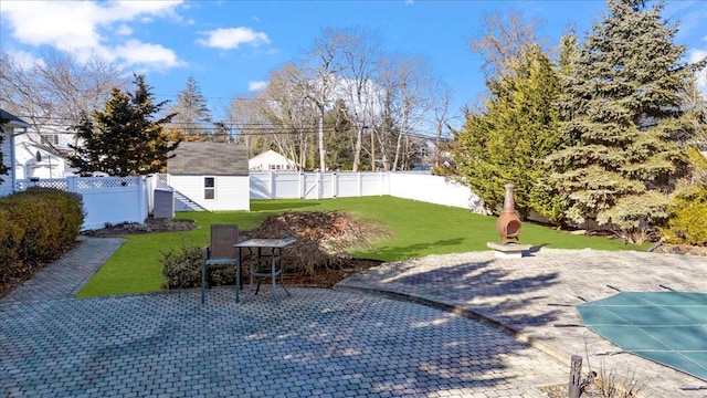 view of patio / terrace with a storage unit, an outdoor structure, a fenced backyard, and a covered pool