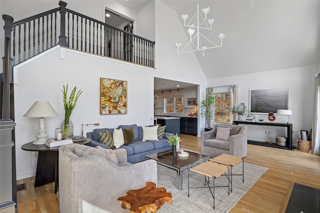 living area with light wood-style floors, a high ceiling, and a chandelier