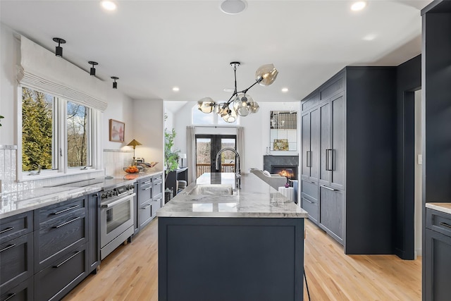 kitchen with decorative backsplash, electric range, light stone counters, and a sink