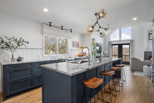 kitchen with french doors, light stone countertops, a healthy amount of sunlight, and light wood-style flooring