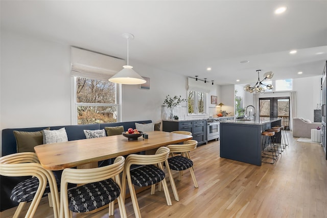 dining space featuring recessed lighting, light wood-style flooring, and an inviting chandelier