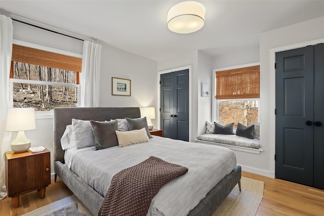 bedroom with a closet, light wood-style flooring, and baseboards