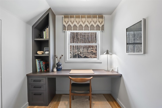 home office with baseboards, wood finished floors, and built in study area