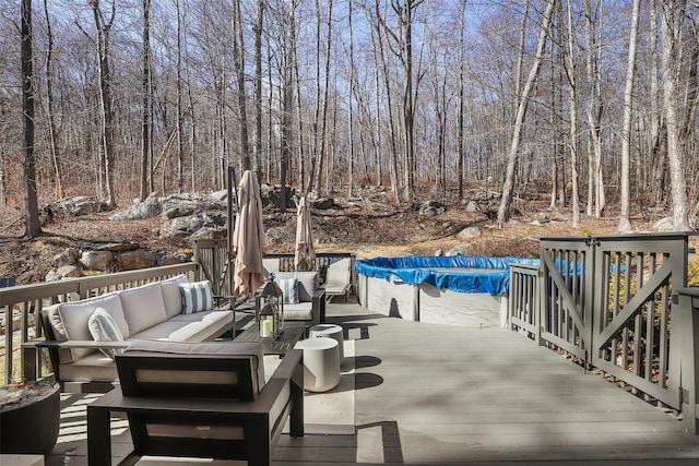 wooden deck with a covered pool, outdoor lounge area, and a view of trees