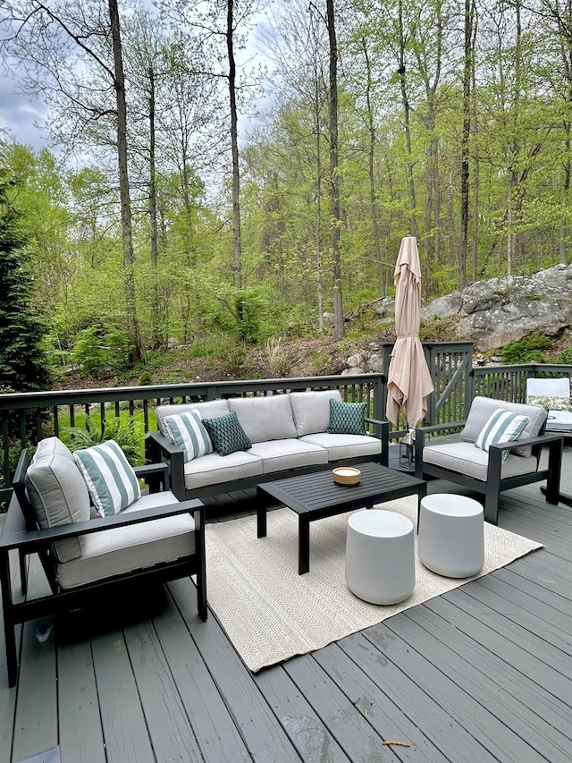 wooden deck with a view of trees and an outdoor hangout area