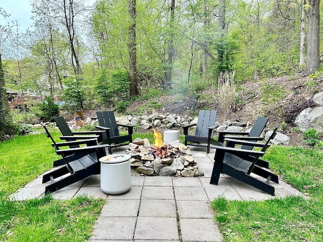 view of patio with a fire pit and a view of trees