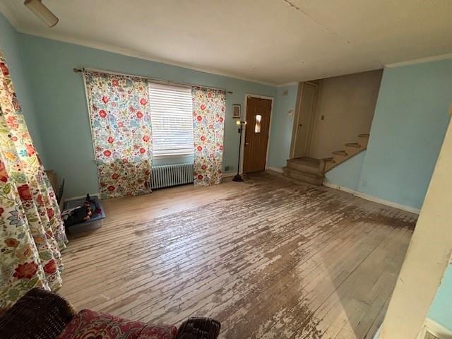 entryway with crown molding, stairway, radiator heating unit, baseboards, and hardwood / wood-style flooring