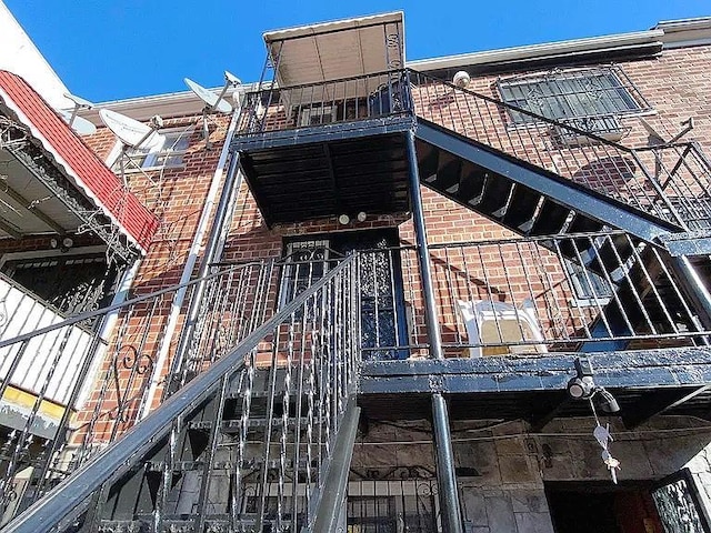 exterior space with brick siding and a balcony