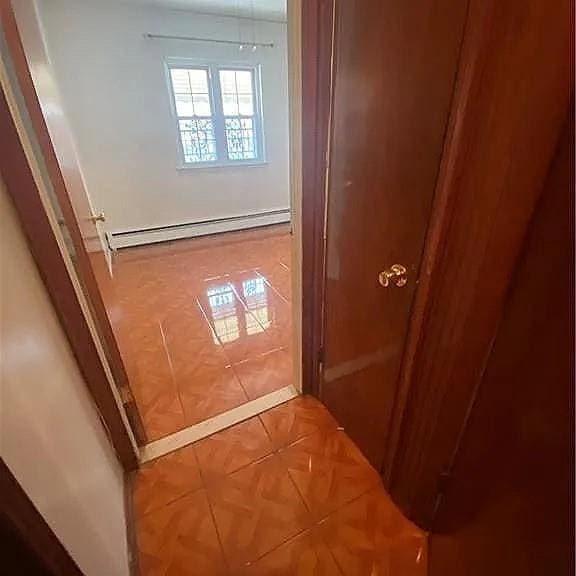 hall with baseboard heating and tile patterned floors