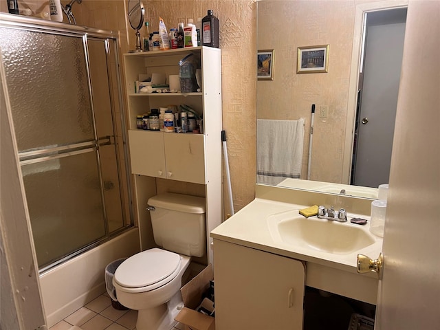 bathroom featuring shower / bath combination with glass door, a textured wall, toilet, vanity, and tile patterned floors