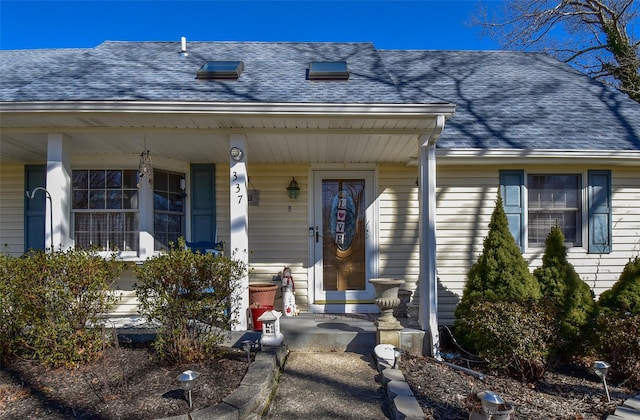 entrance to property featuring a porch and roof with shingles