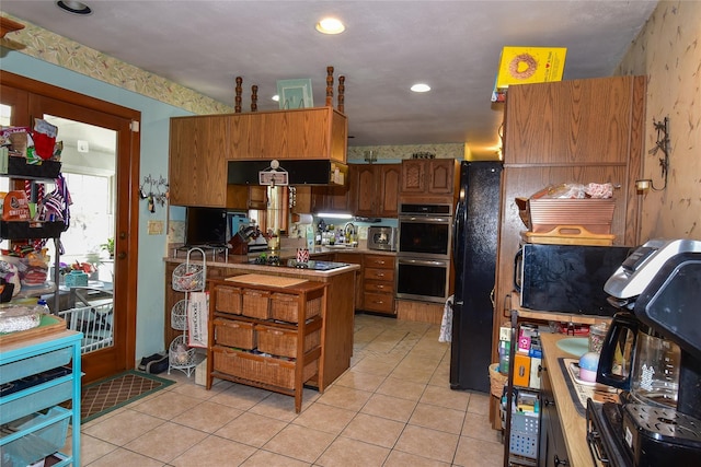 kitchen featuring light tile patterned floors, black appliances, a sink, and brown cabinets