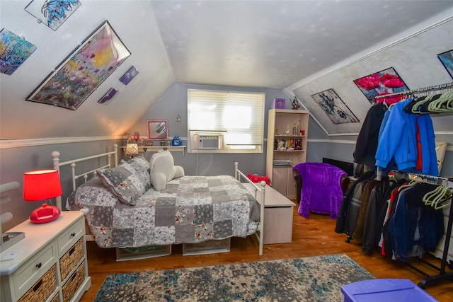 bedroom featuring cooling unit, vaulted ceiling, and wood finished floors