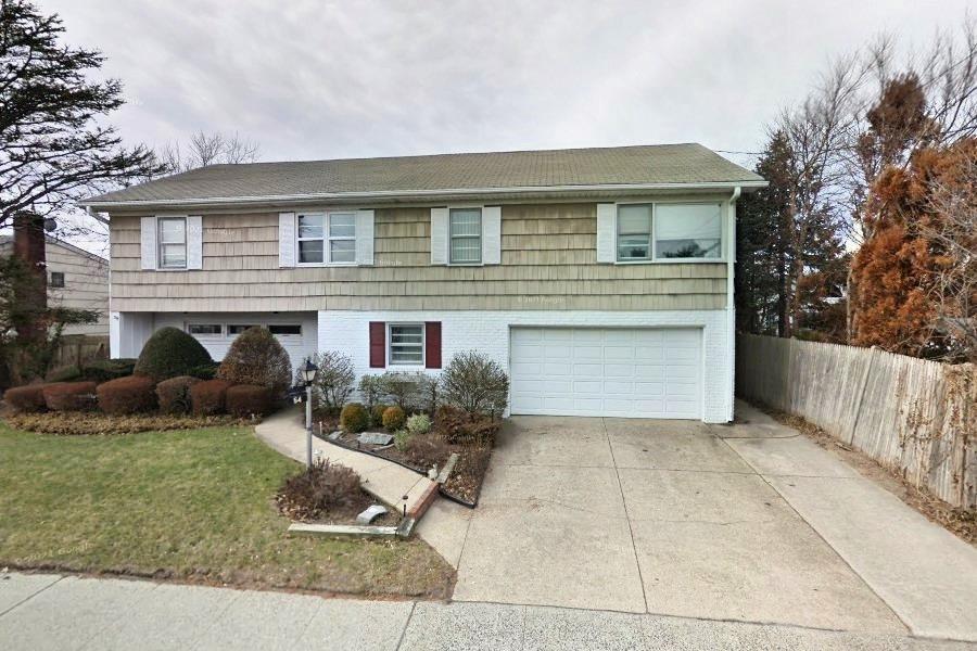 colonial-style house with brick siding, an attached garage, fence, driveway, and a front lawn