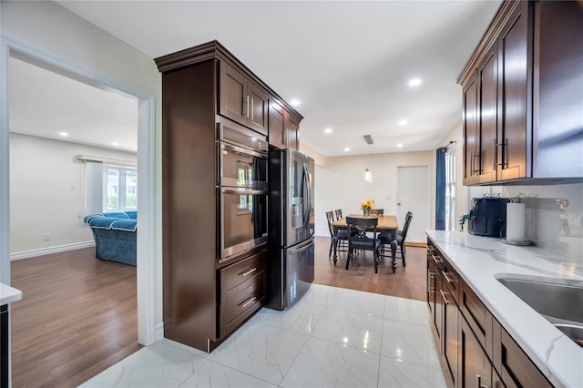 kitchen featuring marble finish floor, recessed lighting, appliances with stainless steel finishes, light stone countertops, and baseboards