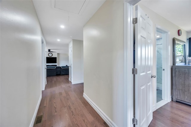 corridor with visible vents, wood finished floors, attic access, and baseboards