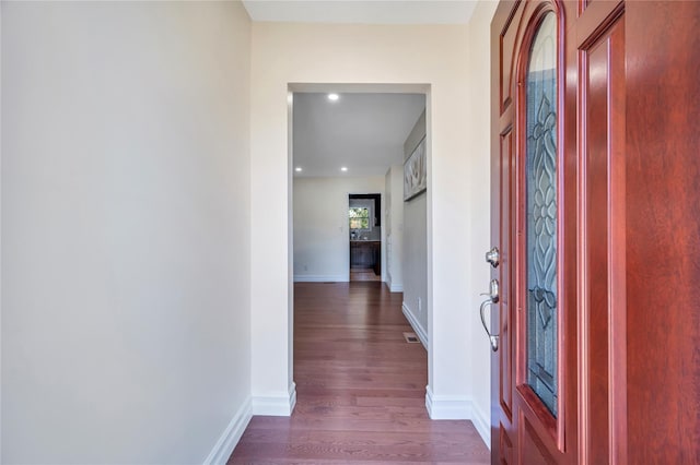 corridor with visible vents, baseboards, and dark wood-type flooring