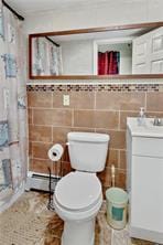 full bathroom featuring curtained shower, tile walls, and toilet