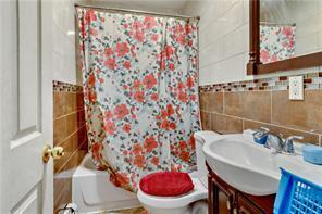 bathroom with shower / bathtub combination with curtain, toilet, tile walls, and vanity