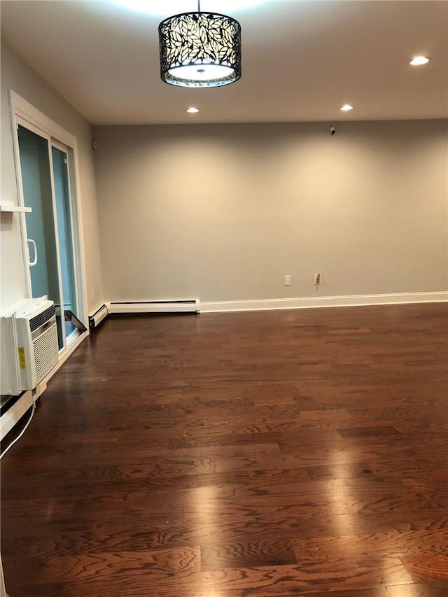 empty room featuring a baseboard heating unit, baseboards, dark wood finished floors, and recessed lighting