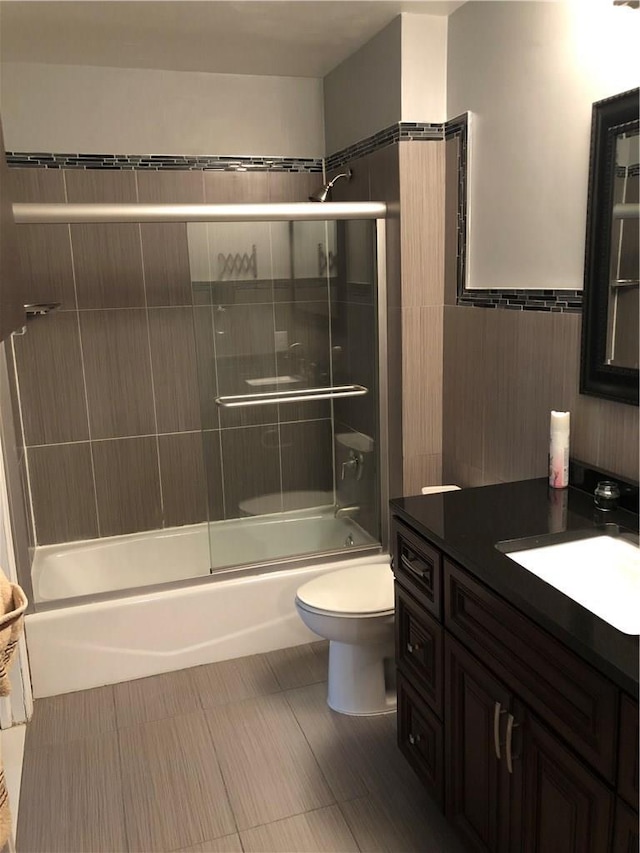 full bathroom with combined bath / shower with glass door, vanity, and toilet