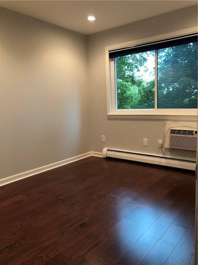 empty room with a wall unit AC, recessed lighting, a baseboard heating unit, wood finished floors, and baseboards