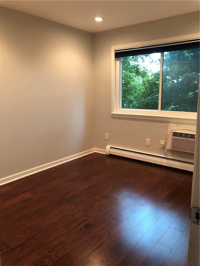 empty room with baseboards, baseboard heating, dark wood finished floors, and recessed lighting