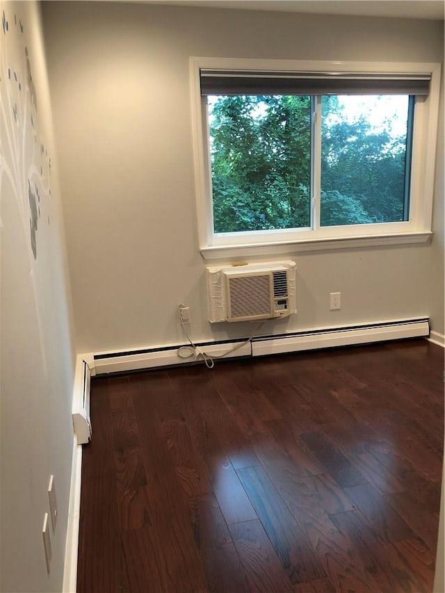 unfurnished room with a healthy amount of sunlight, a baseboard radiator, a wall unit AC, and wood finished floors