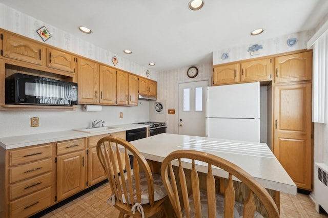 kitchen with a sink, black appliances, light countertops, and wallpapered walls