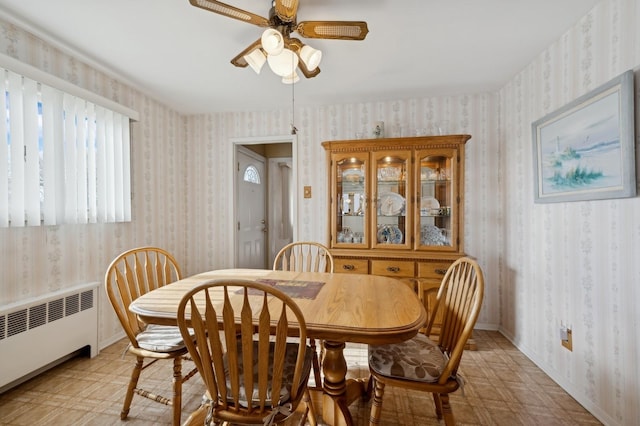 dining room with a ceiling fan, baseboards, radiator, light floors, and wallpapered walls