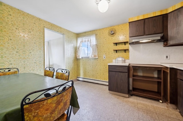 kitchen featuring dark brown cabinetry, under cabinet range hood, a baseboard heating unit, light countertops, and wallpapered walls