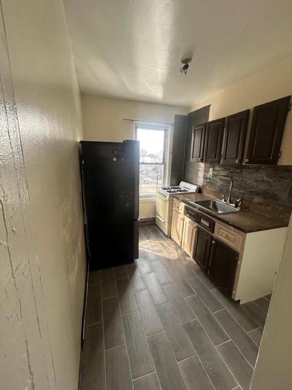 kitchen with white range with gas stovetop, dark countertops, freestanding refrigerator, a sink, and backsplash