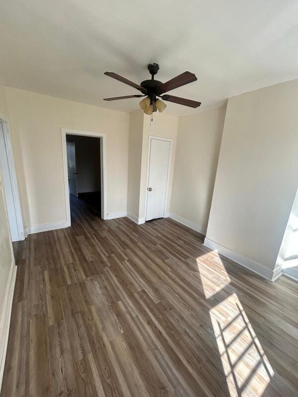 unfurnished bedroom with a ceiling fan, dark wood-style flooring, a closet, and baseboards