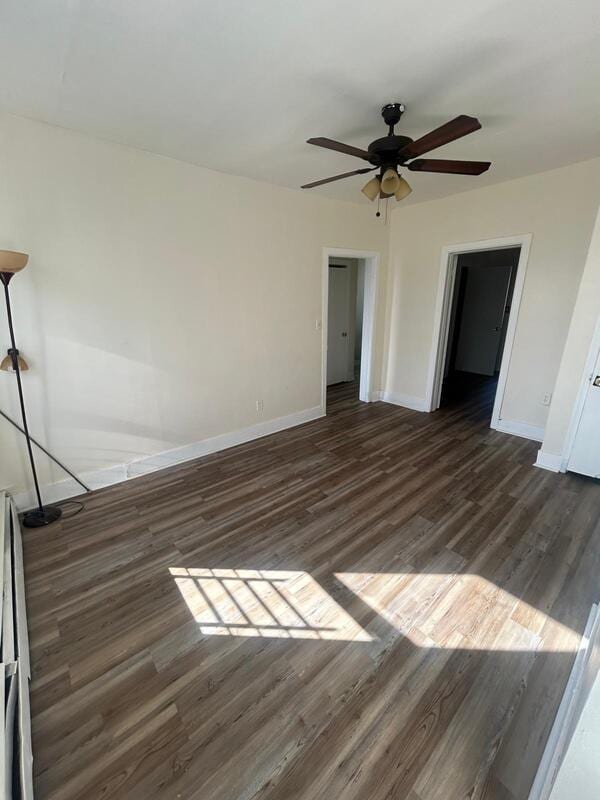 unfurnished bedroom featuring a ceiling fan, baseboards, and dark wood-type flooring