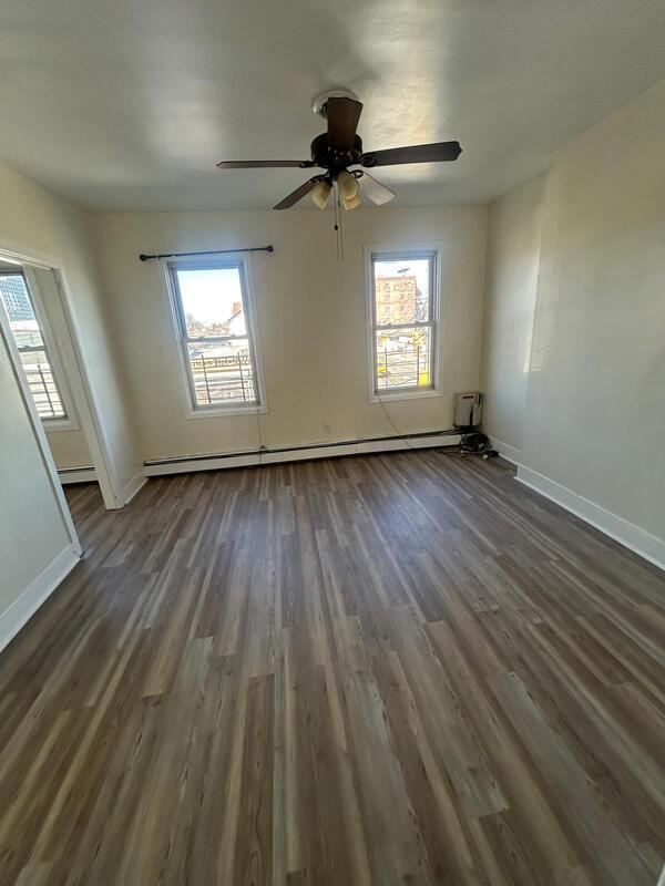 unfurnished room featuring a baseboard heating unit, a wealth of natural light, baseboards, and dark wood-style floors