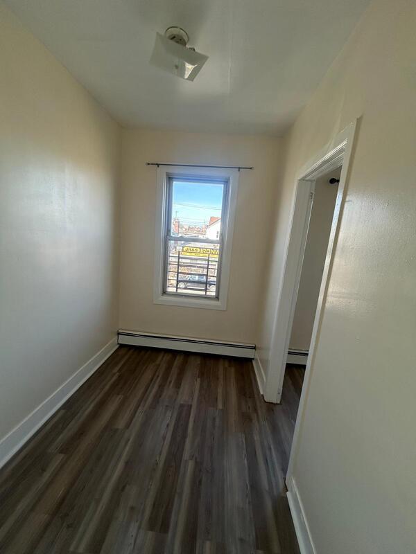 spare room with a baseboard heating unit, dark wood-type flooring, and baseboards