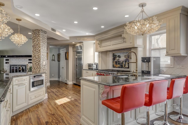 kitchen featuring a peninsula, a brick fireplace, a kitchen bar, and dark stone counters